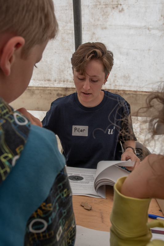 Studentin und Expertin, die nachschlägt, um den kleinen Archäologinnen und Archäologen genaue Informationen zu vermitteln.