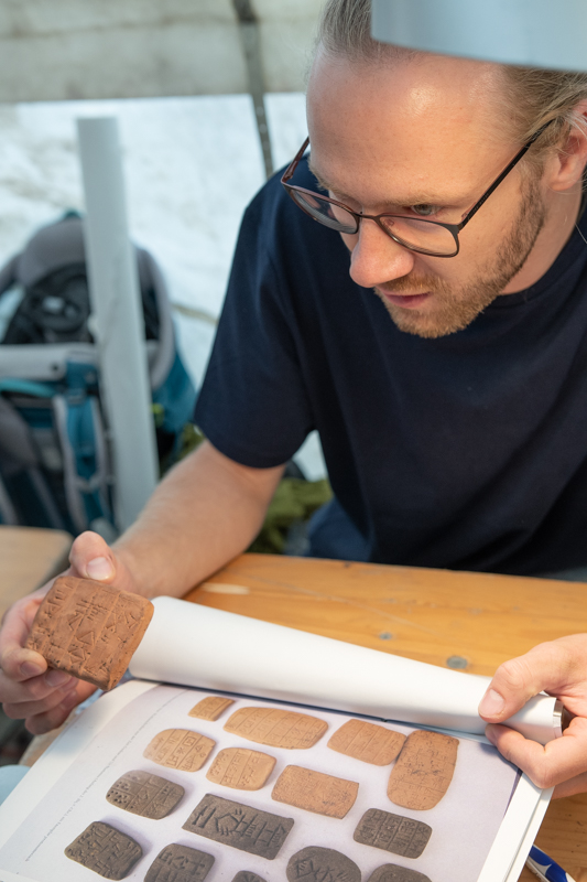 Student mit dem Heft zum Nachschlagen für die Kleinfunde in der Hand.